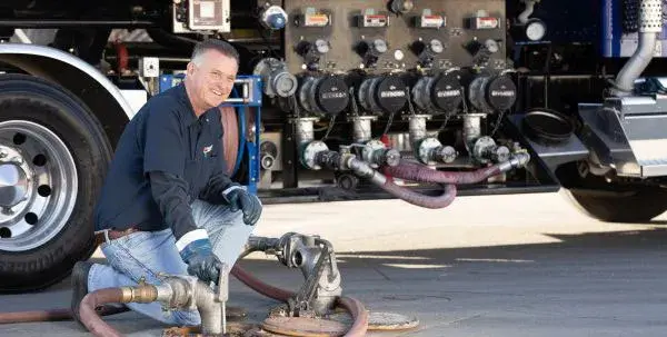 Flyers Fuel Transportation driver filling underground fuel tanks at customer delivery site.