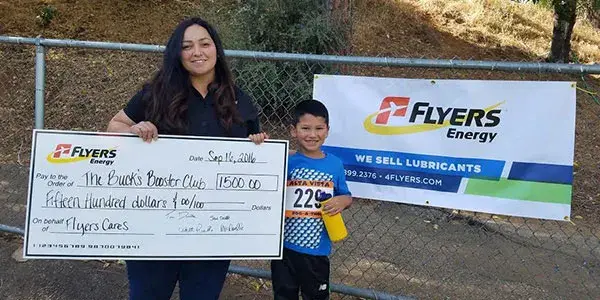 Flyers Team member holding up a large Flyers donation check in the amount of $1500