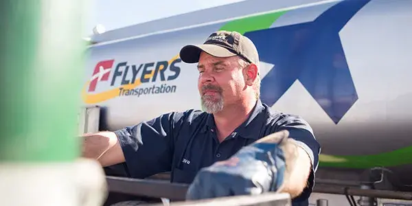 Driver leaning on gate in front of Flyers transportation vehicle.