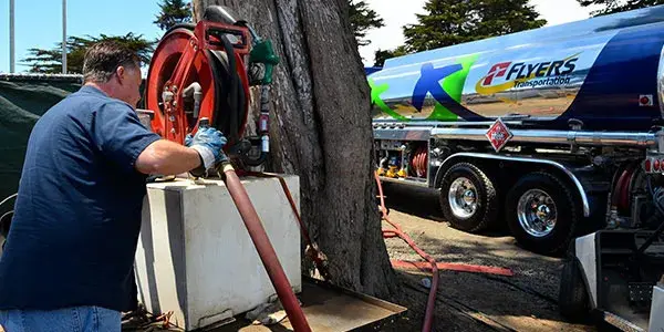 Driver winding red hose near Flyers fuel truck.
